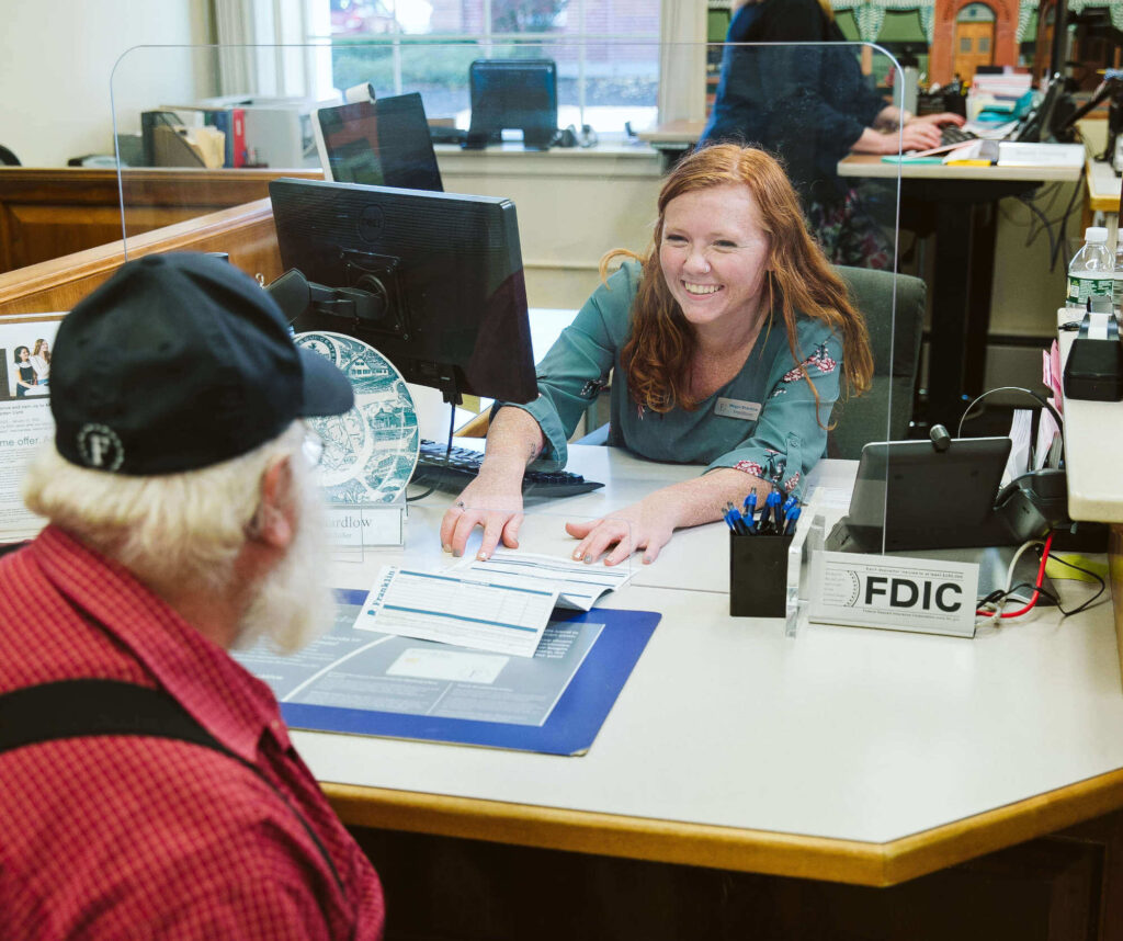 A female bank teller helping an older man sign up for an account