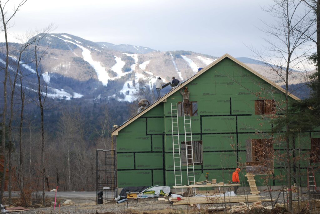 A group of men building a new house with a ski mountain in the background