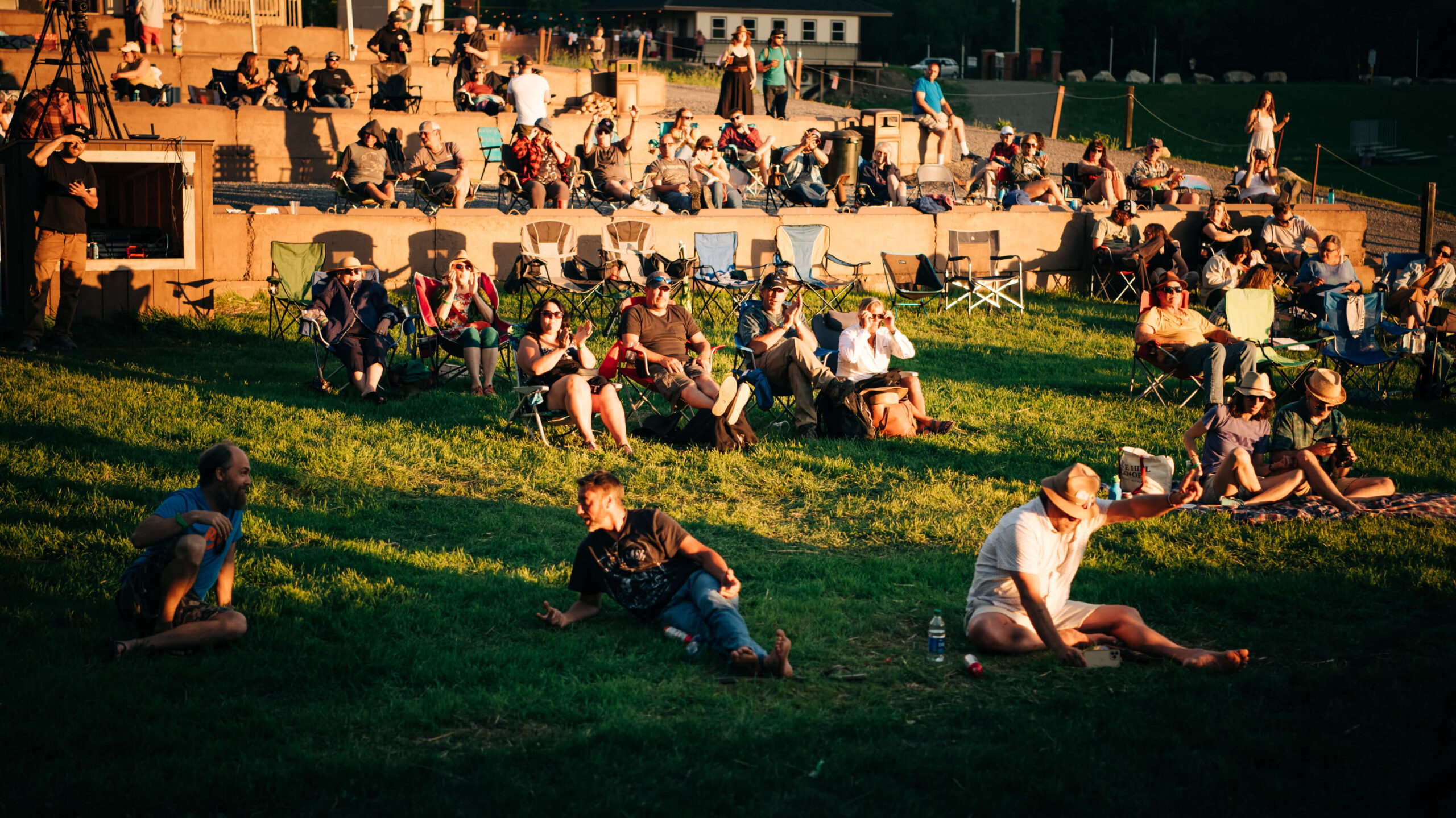 A group of people lounge on the grass while chatting during the Sandy River Music Festival in Farmington, Maine. Photography by Sharyn Peavey Photography.