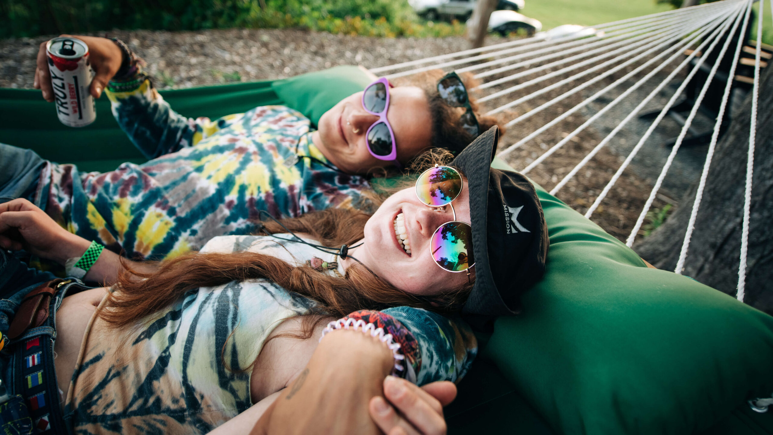 A man and woman laugh while swinging on a hammock at the Sandy River Music Festival in Farmington, Maine. Photography by Sharyn Peavey Photography.
