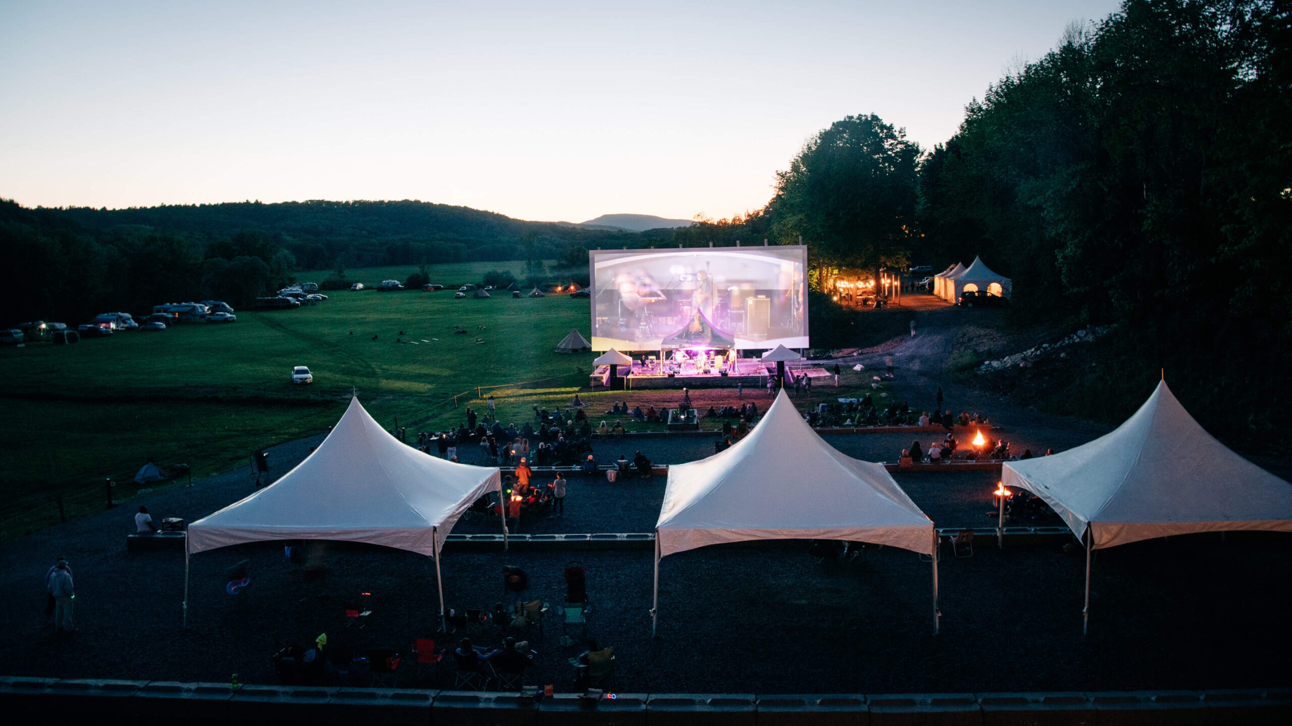A large screen in the distance shows a musical performance during the Sandy River Music Festival in Farmington, Maine. Photography by Sharyn Peavey Photography