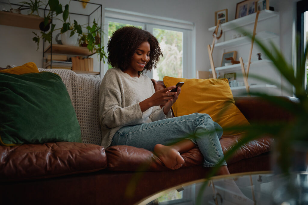 Woman sitting on couch using mobile phone